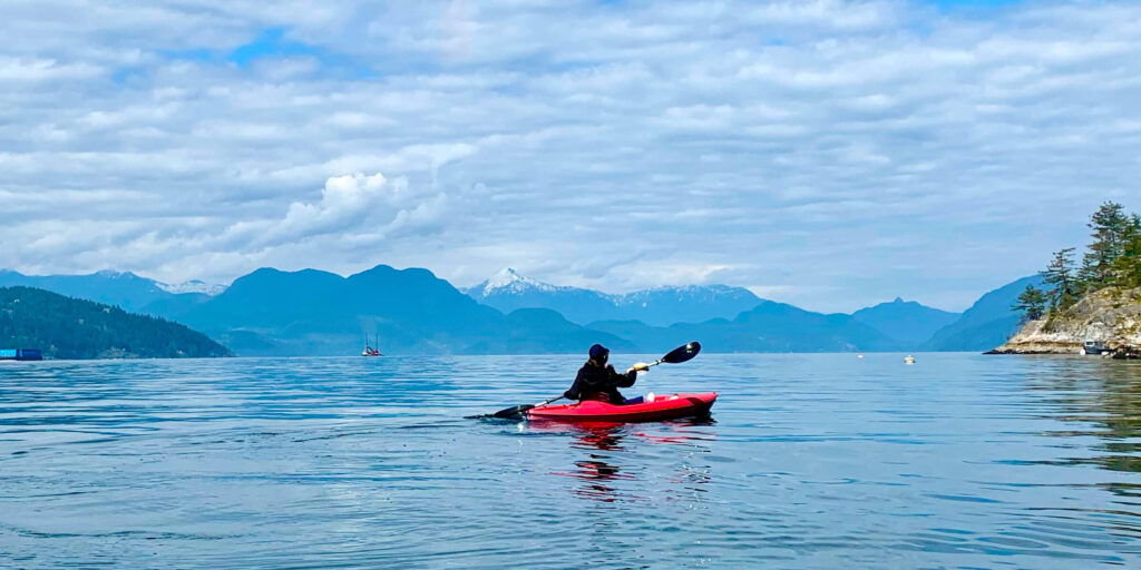 Bowen island sea kayaking: beautiful view of kayak and mountains in the distance.